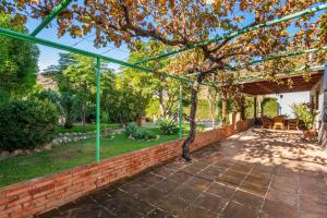 un patio al aire libre con una pared de ladrillo y una pérgola verde en Casa La Encina, en El Chorro