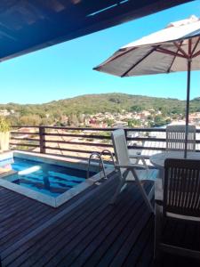 a deck with a chair and an umbrella and a pool at Casa em Geribá com piscina e vista para praia in Búzios +47 photos