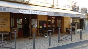 un magasin à l'avant d'un bâtiment avec des tables et des chaises dans l'établissement Hôtel Restaurant Le Victor Hugo, à Sainte-Foy-la-Grande