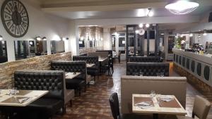 a restaurant with tables and chairs and a clock on the wall at Hôtel Restaurant Le Victor Hugo in Sainte-Foy-la-Grande