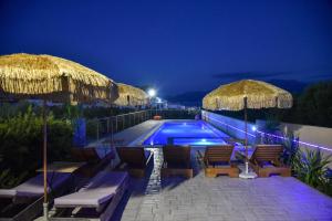 a swimming pool with chairs and umbrellas at night at VillaBayViewCrete in Hersonissos