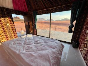 a bed in a room with a view of the desert at Wadi Rum Desert Adventures in Wadi Rum