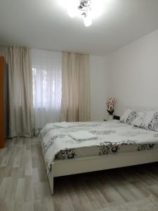a white bedroom with a bed and a window at Criss Apartament in Suceava