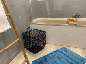 een badkamer met een zwarte mand naast een bad bij Le Terrier du Katz in Dabo