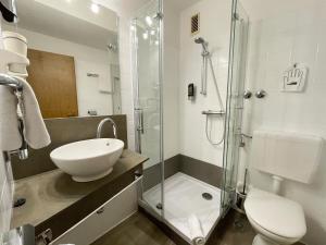 a bathroom with a sink and a glass shower at Brenner Hotel in Bielefeld