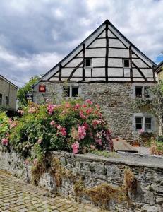 a building with flowers in front of a stone wall at Mante et Nana in Durbuy