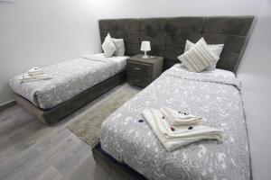 a bedroom with two beds and a night stand at Dakhla White Hotel in Dakhla