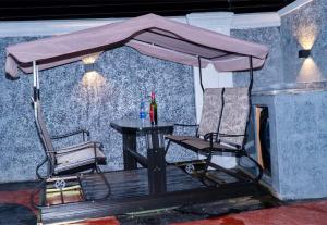 einen Tisch und einen Stuhl unter einem Schirm auf einem Deck in der Unterkunft Westpark Luxury Apartments in Ikeja