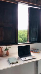 un ordinateur portable assis sur un bureau avec une fenêtre dans l'établissement Morada Cacauêra, à Itacaré