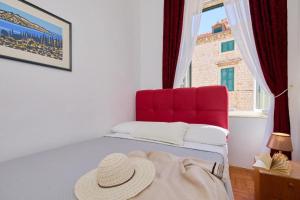 a hat sitting on a bed in a room with a window at Festa Stradun Apartment in Dubrovnik