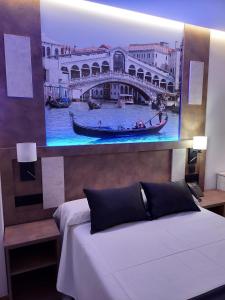 sypialnia z obrazem mostu i łóżkiem w obiekcie HOTEL BOUTIQUE DOÑA MANUELA w mieście Tomelloso