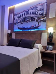 a bedroom with a bed with a painting on the wall at HOTEL BOUTIQUE DOÑA MANUELA in Tomelloso