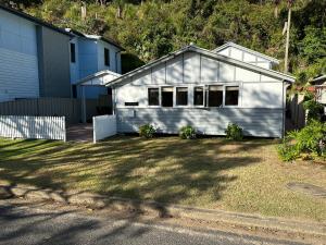 a white house in a yard next to a house at Patonga Holiday Home in Patonga