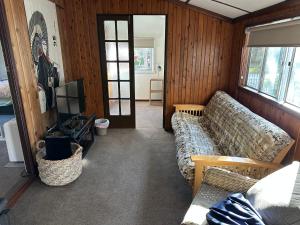 a living room with a couch and a television at Patonga Holiday Home in Patonga