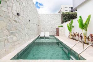 una piscina en una casa con una pared de piedra en Bauten Cabo Branco 206 - completo, 150m da praia, en João Pessoa