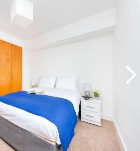 a white bedroom with a large bed and a night stand at Bright, Spacious, Nice Interior, Close to the City, 2 Bedroom Apartment in London