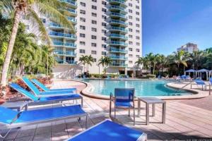 una piscina con sedie a sdraio blu e un hotel di Ocean Reserve Sunny Isles 11th STR-02330 a Miami Beach