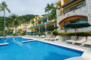 a resort swimming pool with lounge chairs and a building at Camino Real Acapulco Diamante in Acapulco
