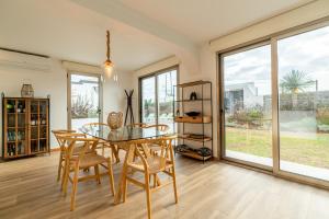 uma sala de jantar com mesa, cadeiras e janelas em Casa Paul do Mar em Paul do Mar