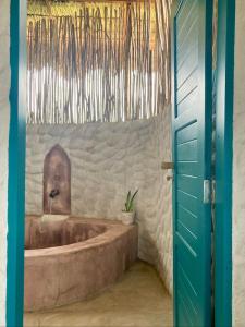 - une baignoire dans une chambre avec une porte bleue dans l'établissement Mangará Pousada, à Praia de Moitas