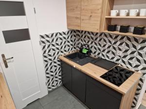 a kitchen with a sink and a patterned wall at Apartamenty w pełni wyposażone w CENTRUM MIASTA in Inowrocław