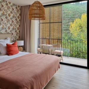- une chambre avec un grand lit et un balcon dans l'établissement Quinta das Levadas - Country House & Nature, à Alvoco das Várzeas