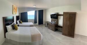 a hotel room with two beds and a television at Hacienda Mazatlán sea view in Mazatlán