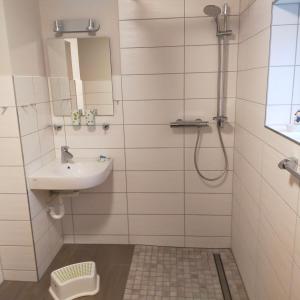 a bathroom with a sink and a shower with a mirror at Ferienwohnung H2 am Hainich 