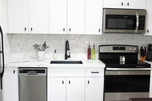 Una cocina con gabinetes blancos, estufa y microondas. en Remodeled Modern Ground Level Apt Blocks to Dwntn - B, en Tempe