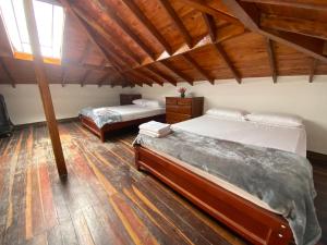 two beds in a room with wooden floors at Duplex By Hope in Guatapé