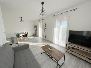 uma sala de estar com um sofá e uma televisão de ecrã plano em 178A - T3 Tout Confort du Gond - 70 m2 em Le Gond-Pontouvre