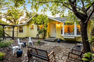 a yellow house with white chairs in front of it at Cloverdale Creekside Retreat in Cloverdale