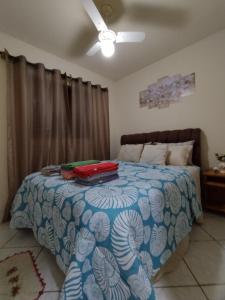 a bedroom with a bed with a blue and white comforter at Casa do adalto in Ilhabela