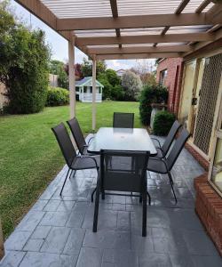 un patio con mesa y sillas bajo una pérgola en Daisy Villa, en Warrnambool