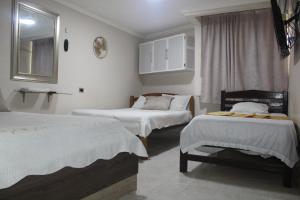里奧阿查的住宿－HOTEL PRIMAVERA RIOHACHA，客房设有三张床、镜子和窗户。