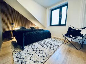 een slaapkamer met een bed, een stoel en een tapijt bij Boutique apartment Heidi with mountain view in Loučná pod Klínovcem