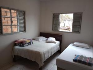 two beds in a room with two windows at Casa da Pirâmide in São Thomé das Letras