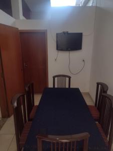 mesa de comedor con sillas y TV en la pared en Apartamento térreo chique, en Guaratinguetá