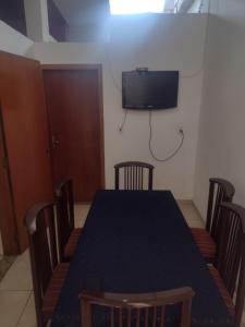 a dining room table with chairs and a tv on the wall at Apartamento térreo chique in Guaratinguetá