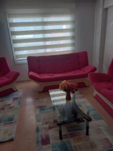 a living room with a red couch and a glass table at EKONOMİ ÜNİVERSİTESİNE 5 Dk. 2+1 EŞYALI DAİRE in Balcova