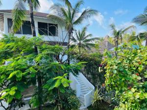 a white house with palm trees and bushes at Dream Luxury B&b Watamu in Watamu