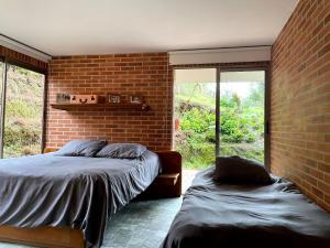 1 dormitorio con cama y pared de ladrillo en Casa 38 de la Parcelación Lagos de Pontezuela en El Retiro