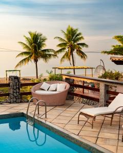 a pool with two chairs and a tub next to the ocean at Pousada Algodão da Praia in Araruama