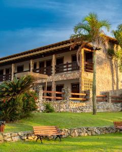 a building with a palm tree and benches in front of it at Pousada Algodão da Praia in Araruama