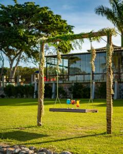 a swing in a park with a building in the background at Pousada Algodão da Praia in Araruama