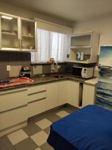 una cucina con armadi bianchi e un letto blu di Apartamento 103 Praia do Ervino - SFS a São Francisco do Sul Altre 43 foto