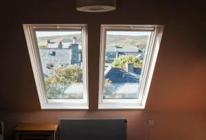 two windows in a room with a view of a city at Nort Bode Apartments in Lerwick