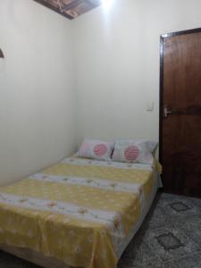 1 dormitorio con 1 cama y puerta de madera en Refúgio sossego (casa de campo), en Camaçari
