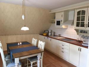 a kitchen with white cabinets and a wooden table with chairs at Ferienwohnung zur Brake in Wieck
