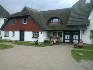 a large white and red house with a patio at Pension Martens - Gaubenwohnung in Wieck